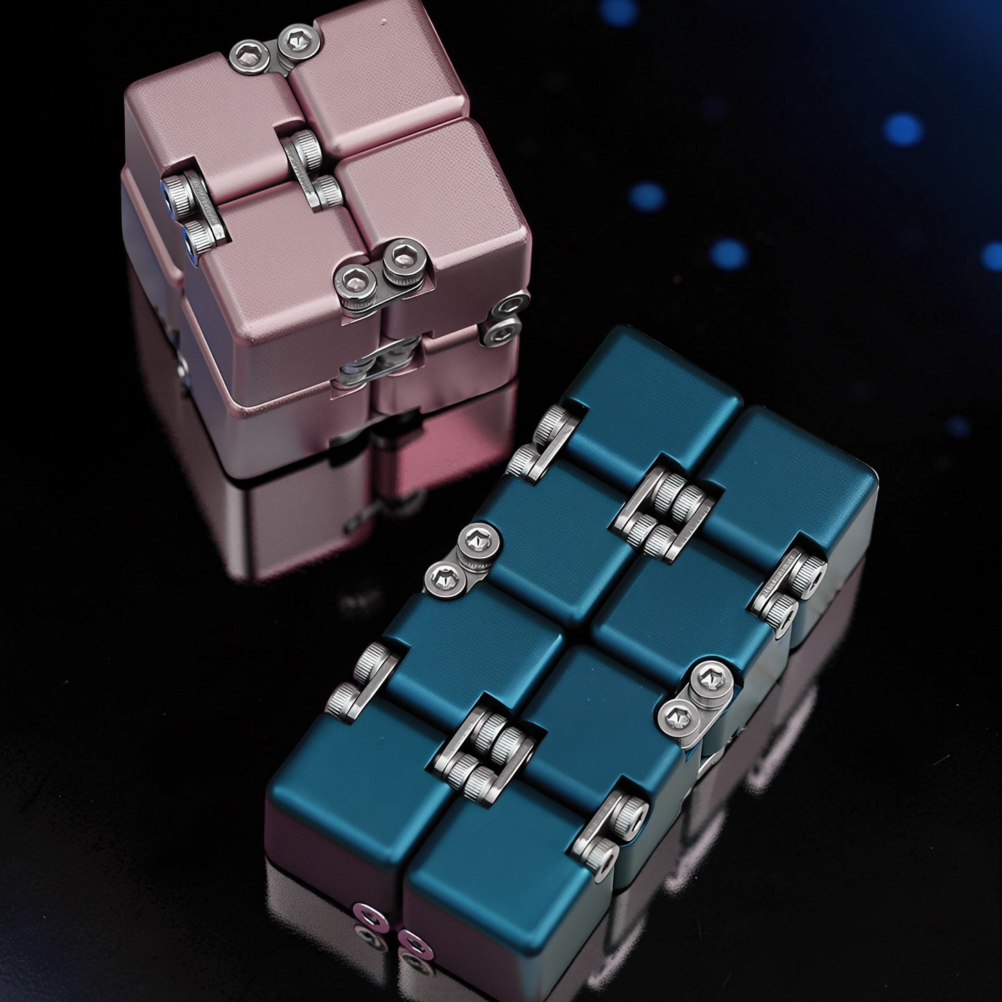 The Curious Mind Unlimited Magic Fidget Cube in rose gold and teal metal, featuring a compact, foldable design with visible screws.