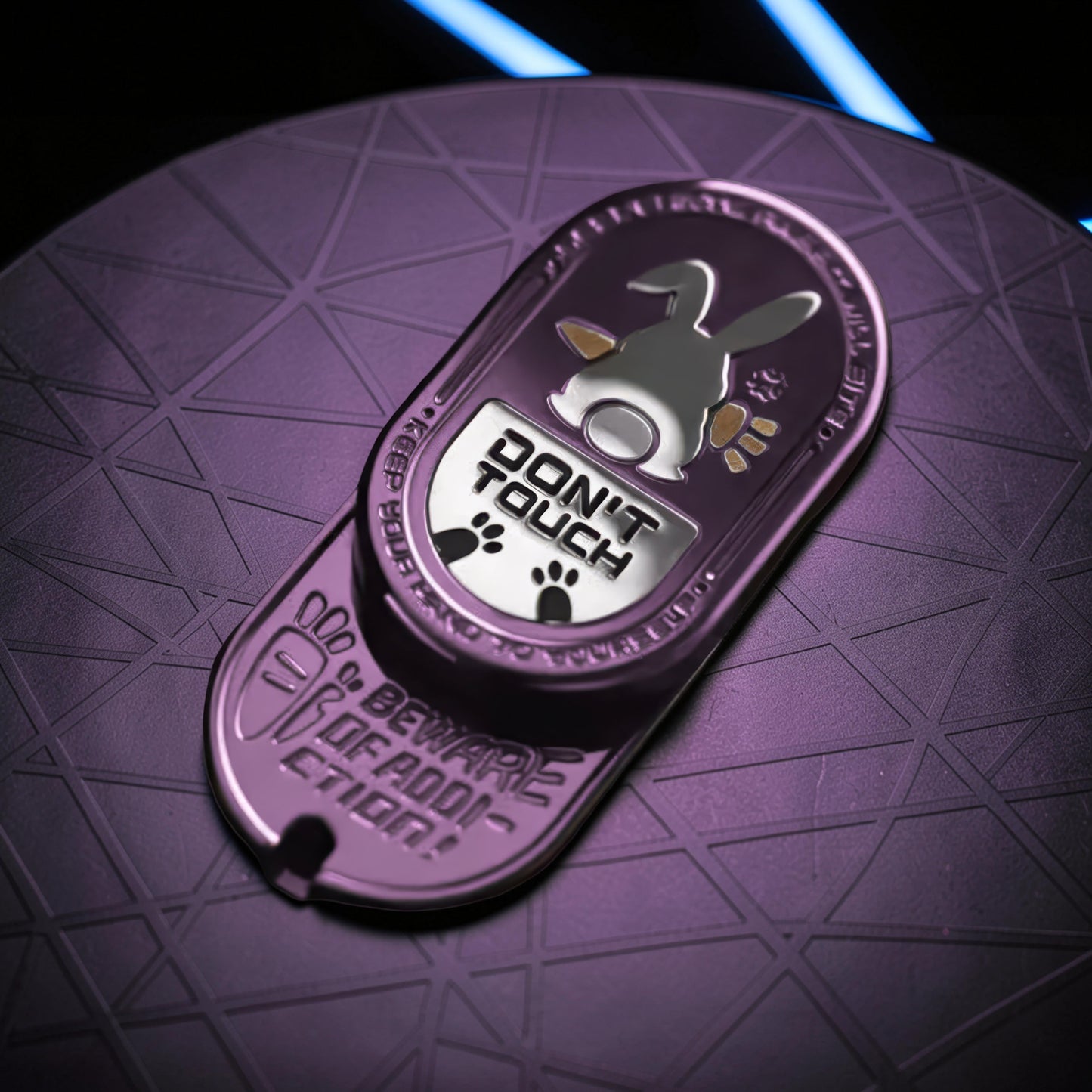 The Curious Mind Don't Touch Rabbit Slider: a purple metal fidget toy with a rabbit graphic and paw prints. Features tactile sliding action.