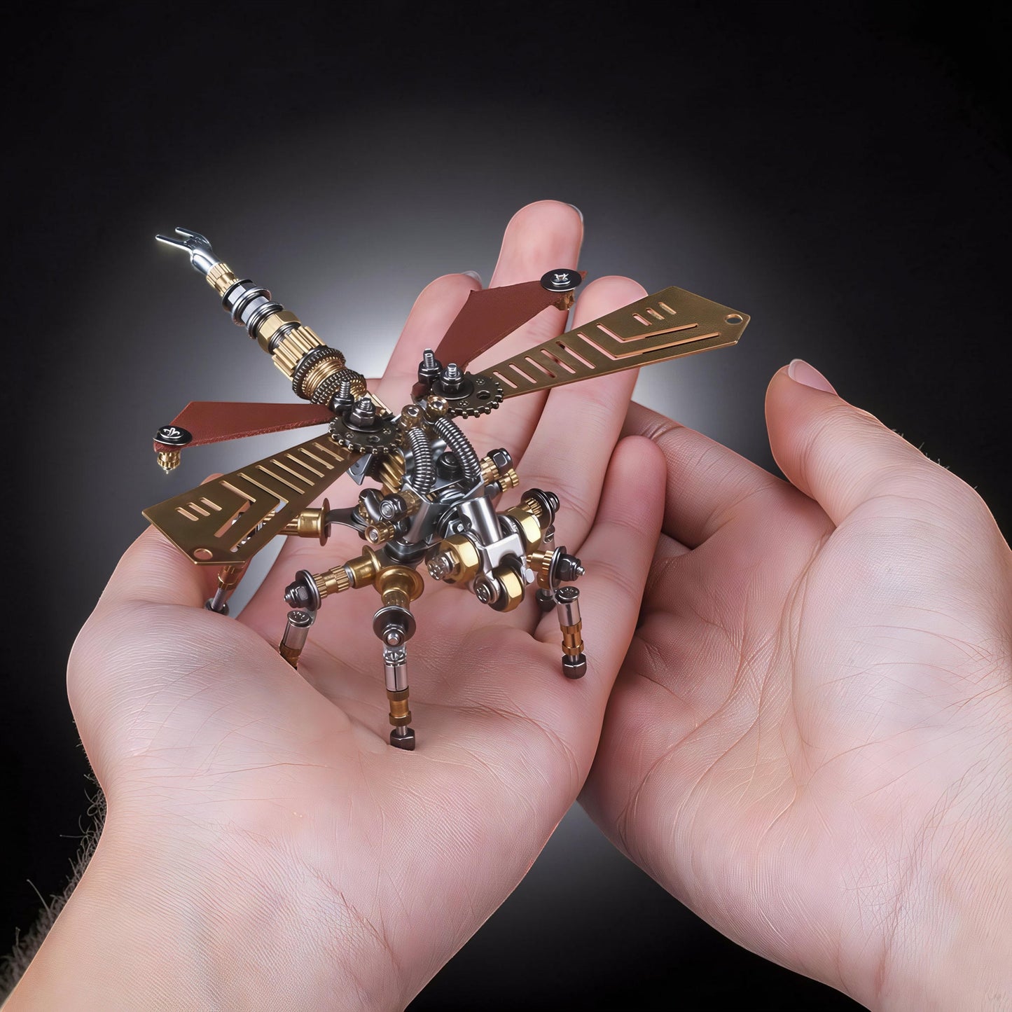 The Curious Mind Dragonfly 3D metal model kit with brass wings and intricate mechanical details held in hands.