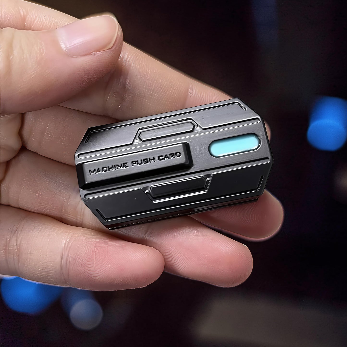 The Curious Mind Luminous Magnetic Haptic Slider fidget toy in black metal with a blue light accent. Features 'MACHINE PUSH CARD' text.