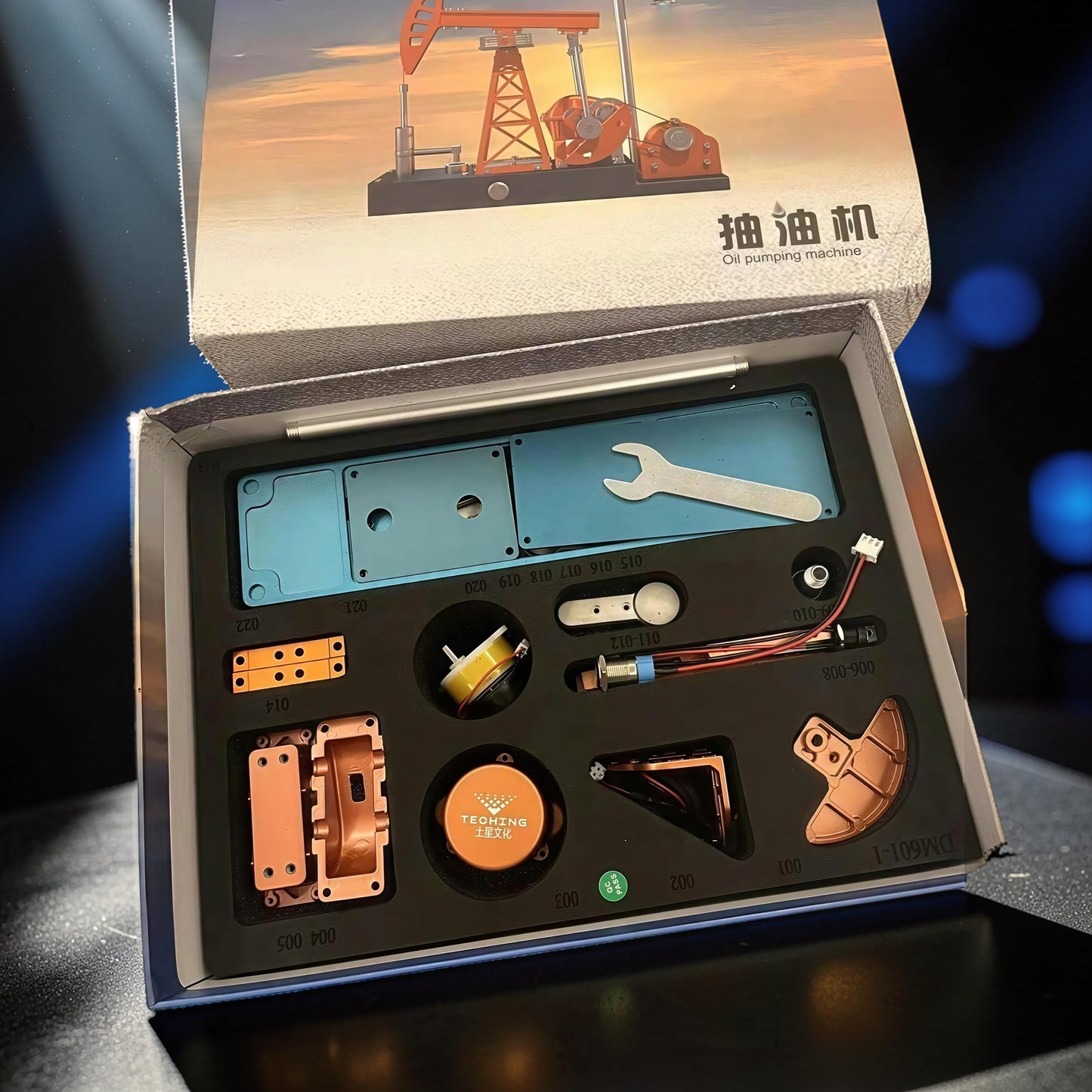 The Curious Mind Oil Derrick Pumping Unit DIY Kit with metal parts and tools laid out in a box.