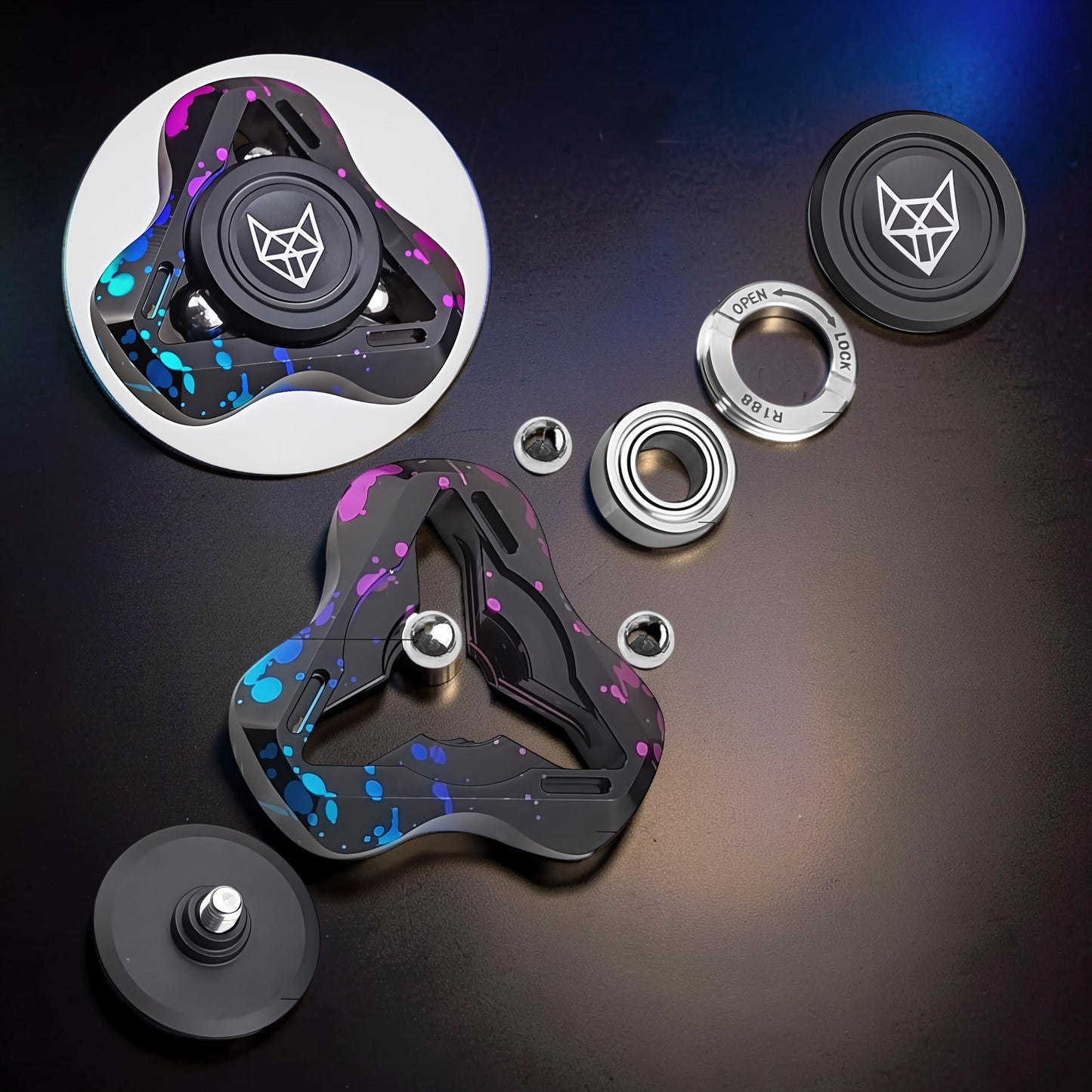 The Curious Mind Spirit Fox Glow Spinner with black, blue, and pink splatter design. Metal construction with R188 bearing.