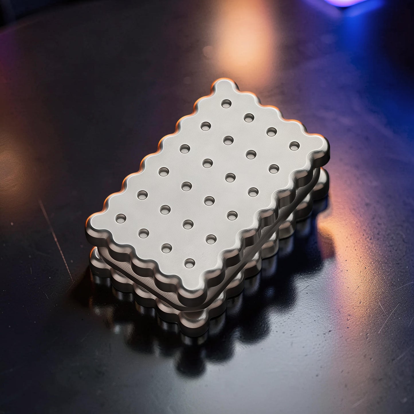 The Curious Mind Biscuit Push Card Slider, a silver metal fidget toy with a biscuit design and textured surface.