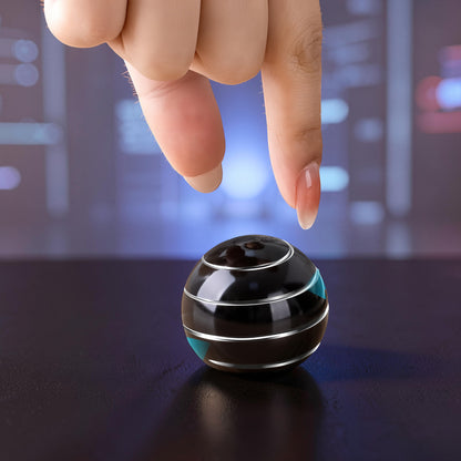 The Curious Mind high-gloss black metal desk fidget ball with silver accents, being touched by fingertips.
