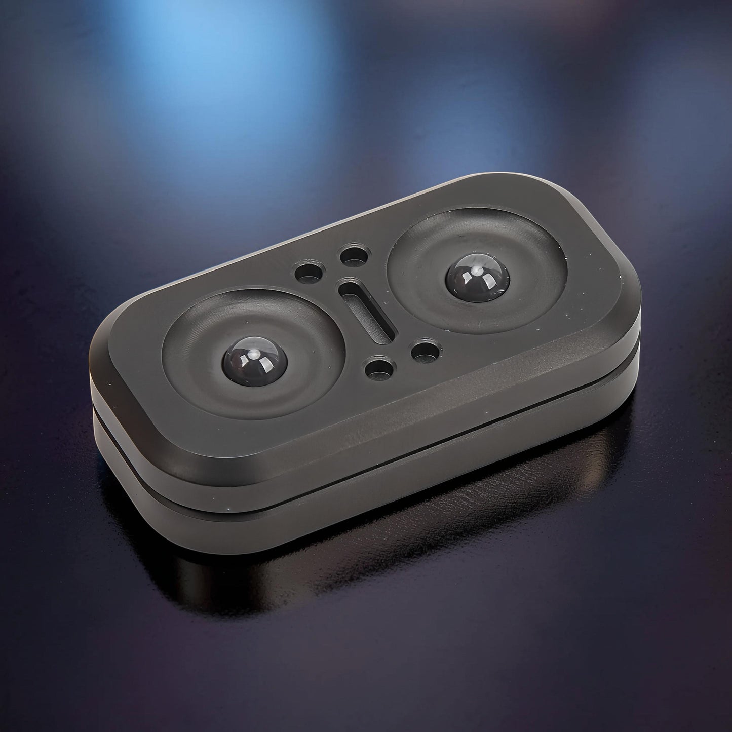 The Curious Mind Owl Push Slider, a compact black metal fidget toy with two circular indentations and a central slot.