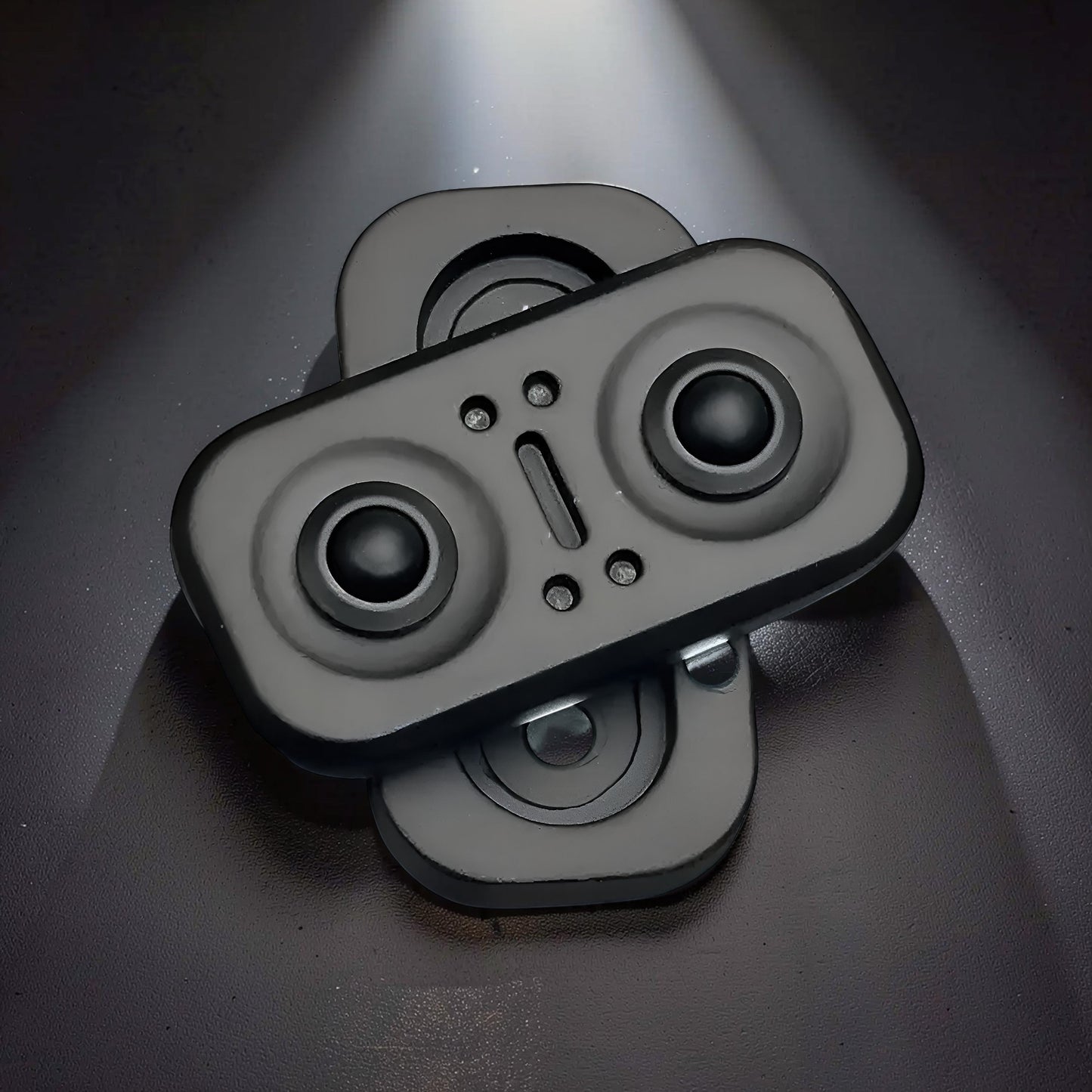 The Curious Mind Owl Push Slider, a compact black metal fidget toy with two circular buttons and a central slider.