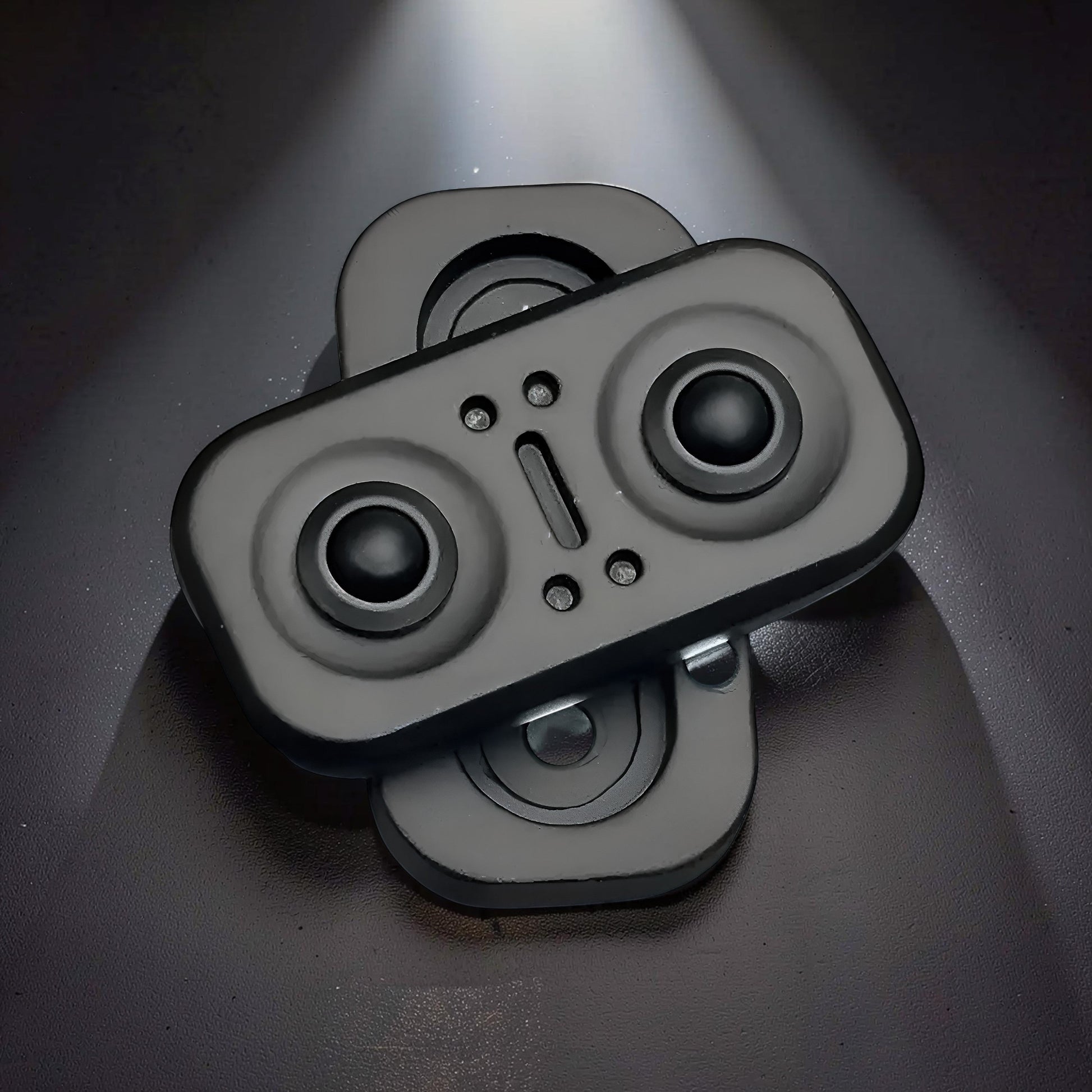 The Curious Mind Owl Push Slider, a compact black metal fidget toy with two circular buttons and a central slider.