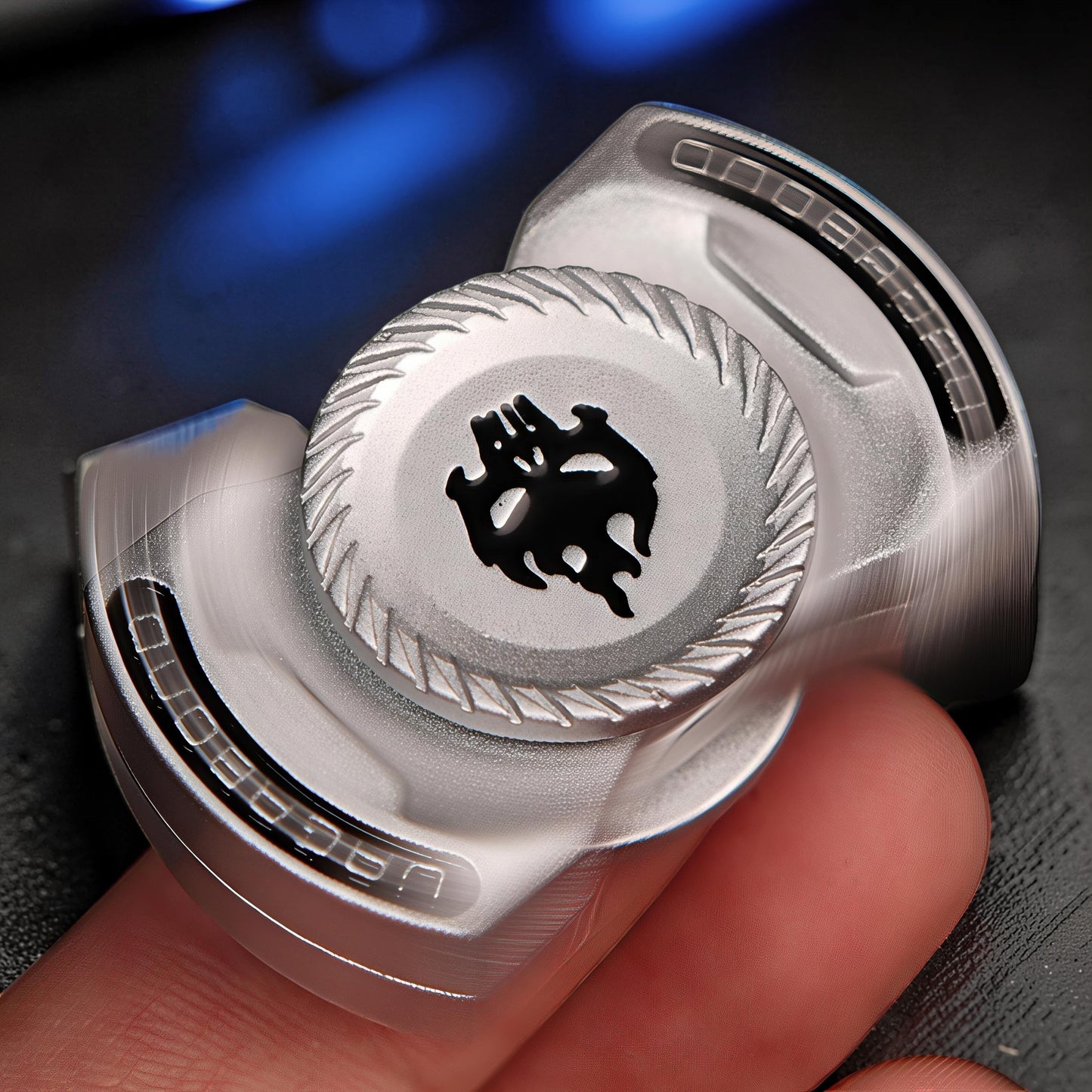 The Curious Mind Butterfly Plus metal spinner in black with a skull design, held by fingers.