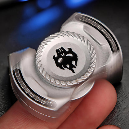 The Curious Mind Butterfly Plus metal spinner in black with a skull design, held by fingers.