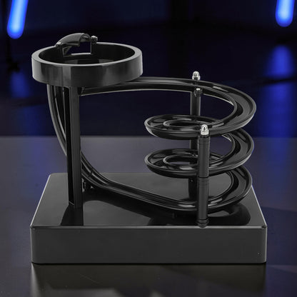 The Curious Mind black electromagnetic perpetual motion machine with a wooden, metal, and magnet construction, featuring a spiraling track for a science display.