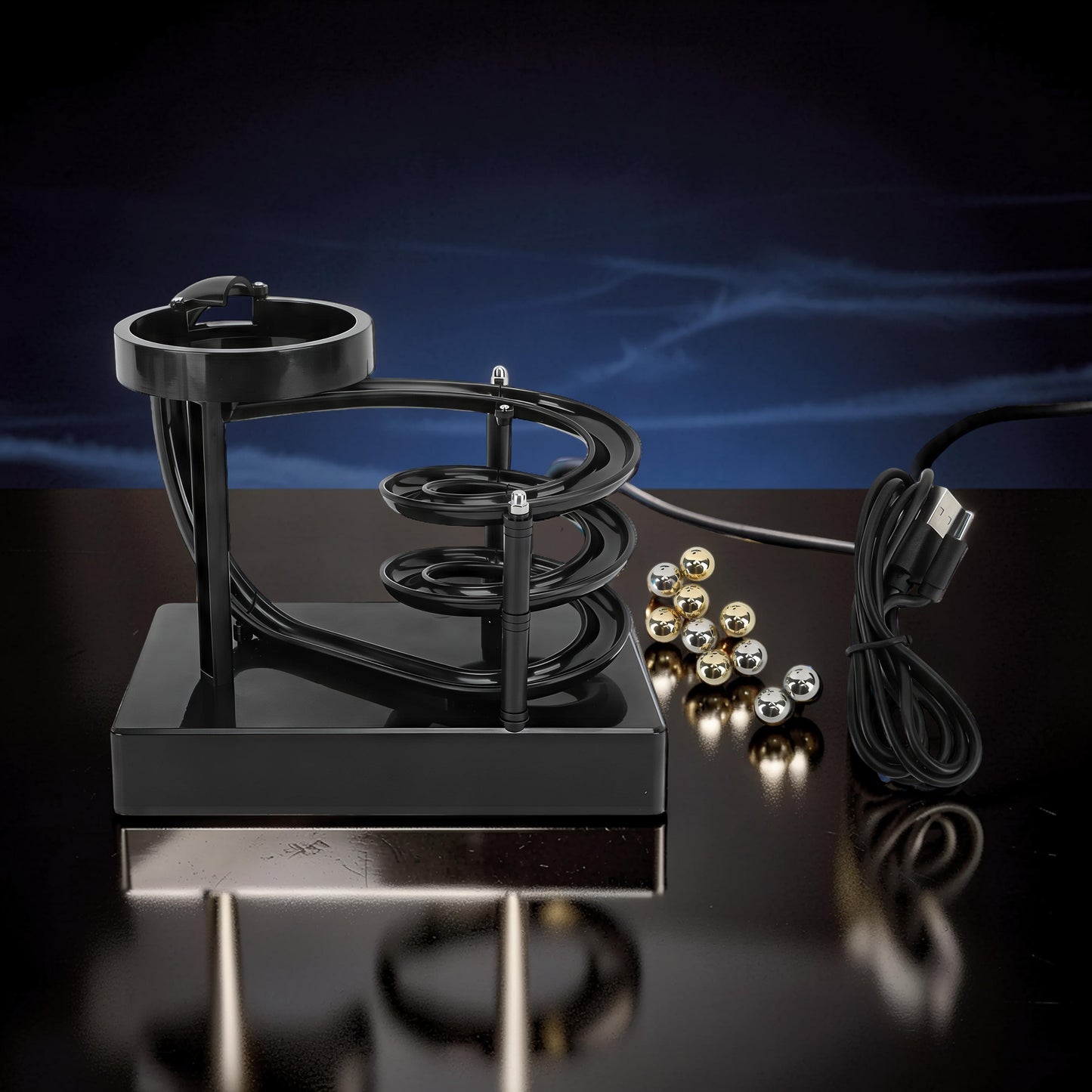 The Curious Mind black electromagnetic perpetual motion machine with silver and gold balls and USB cable.