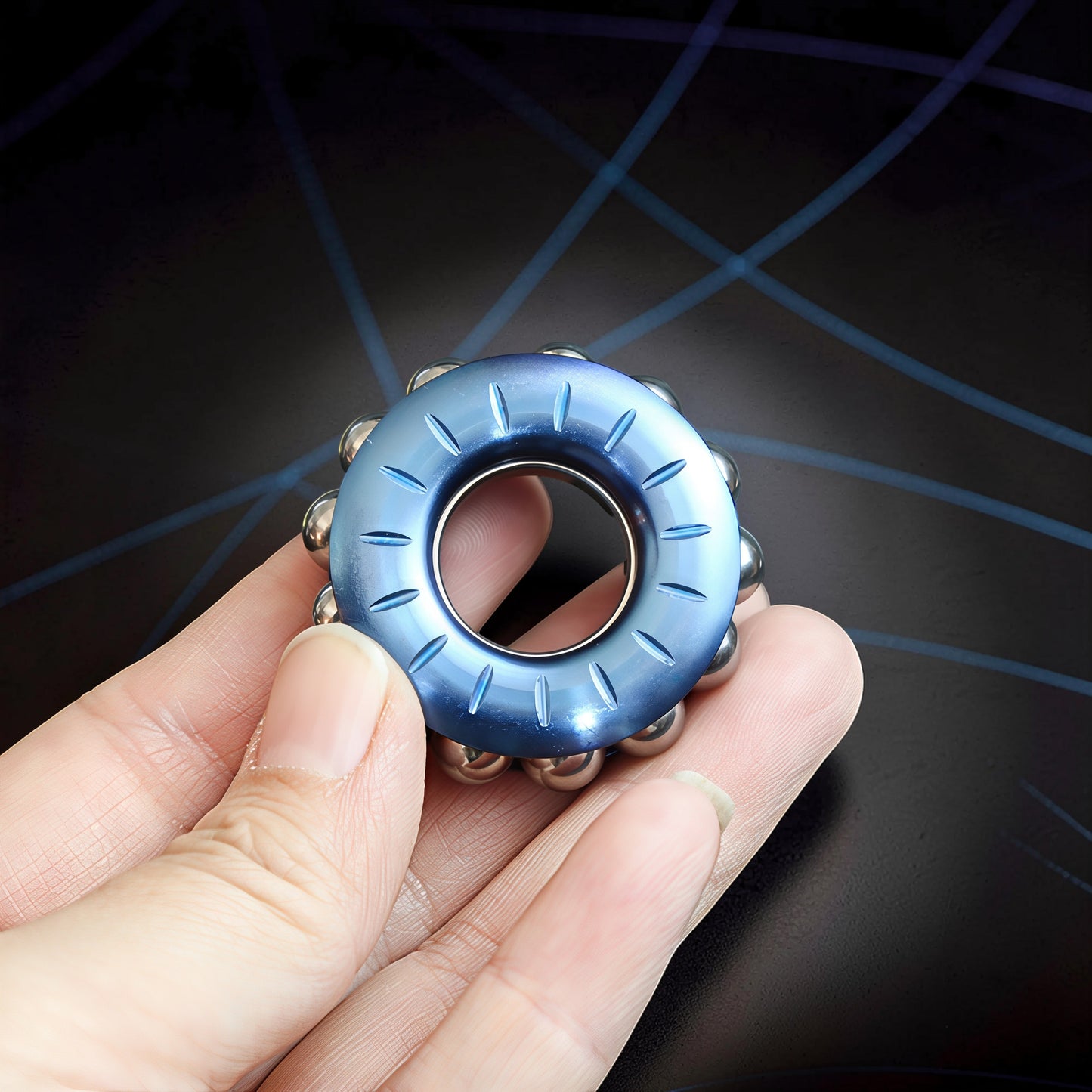 The Curious Mind blue metal bead wheel spinner with carved lines and silver beads, held in a hand.