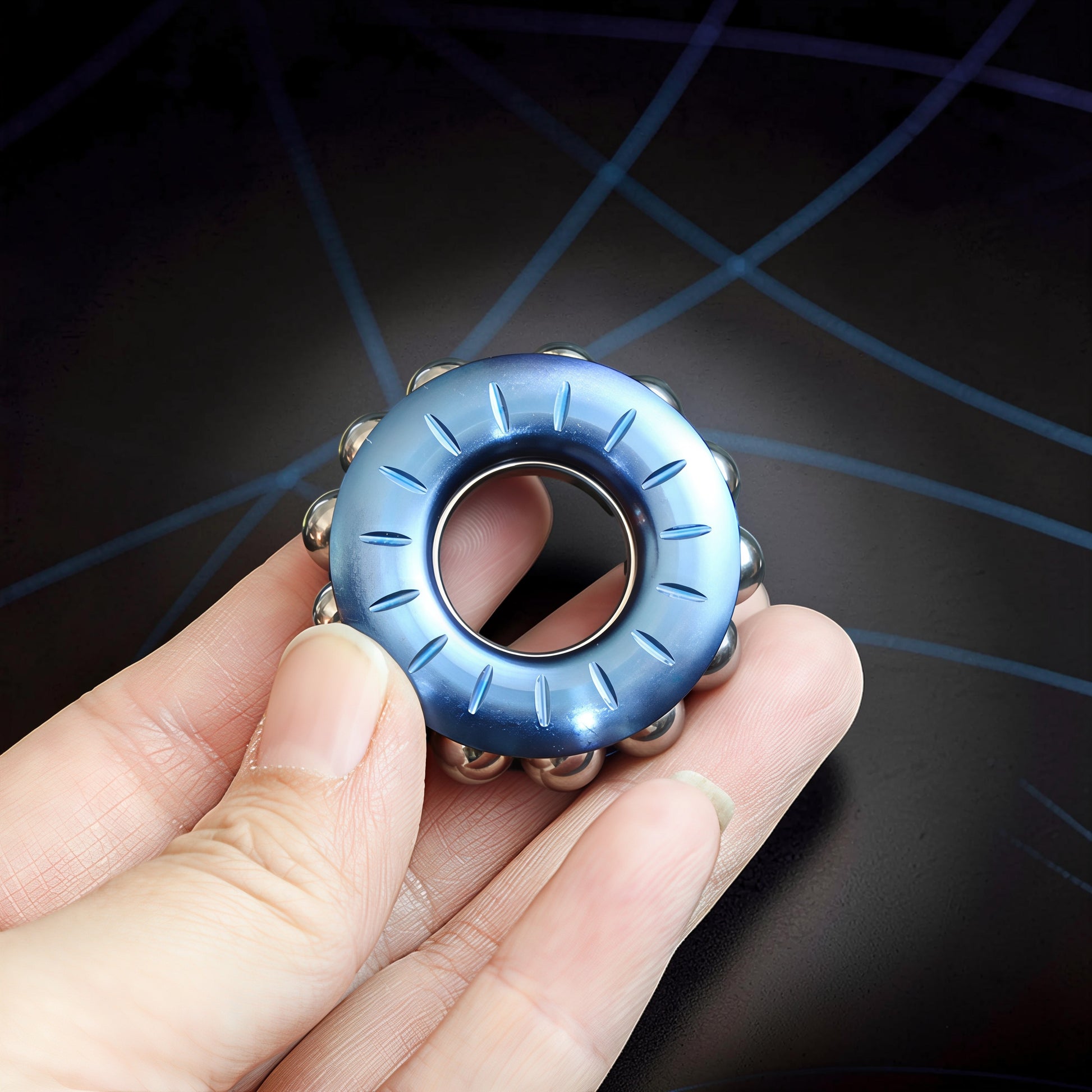 The Curious Mind blue metal bead wheel spinner with carved lines and silver beads, held in a hand.