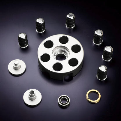 The Curious Mind brass finger gyro spinner components including a central disc, weights, screws, bearing, and retaining ring on a dark background.