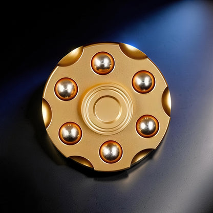 The Curious Mind Brass Finger Gyro Spinner with 7 silver bearings and a central gold bearing. The spinner has a circular, metallic gold finish.