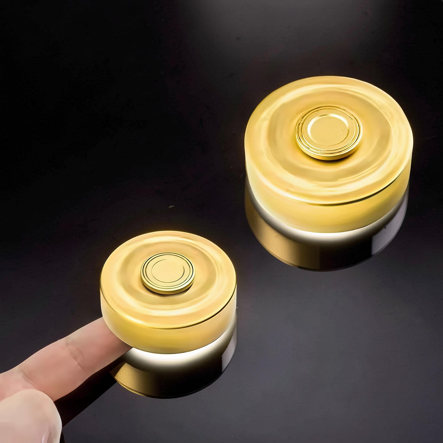 The Curious Mind brass finger gyro spinner with a gold finish, shown on a finger and next to another spinner.