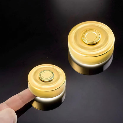 The Curious Mind brass finger gyro spinner with a gold finish, shown on a finger and next to another spinner.