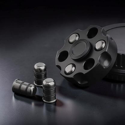 The Curious Mind Brass Finger Gyro Spinner with bullet-shaped weights, black metal, revolver cylinder design.