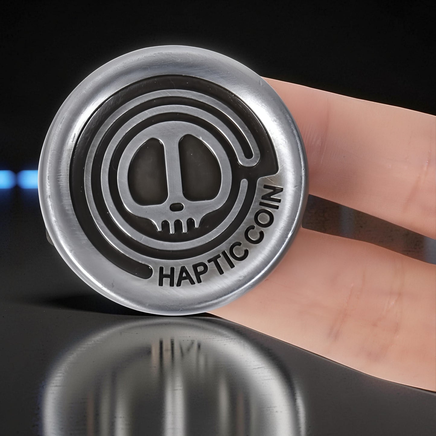 The Curious Mind Demon Coin push card clicker fidget toy, silver metal with skull design and "HAPTIC COIN" text.