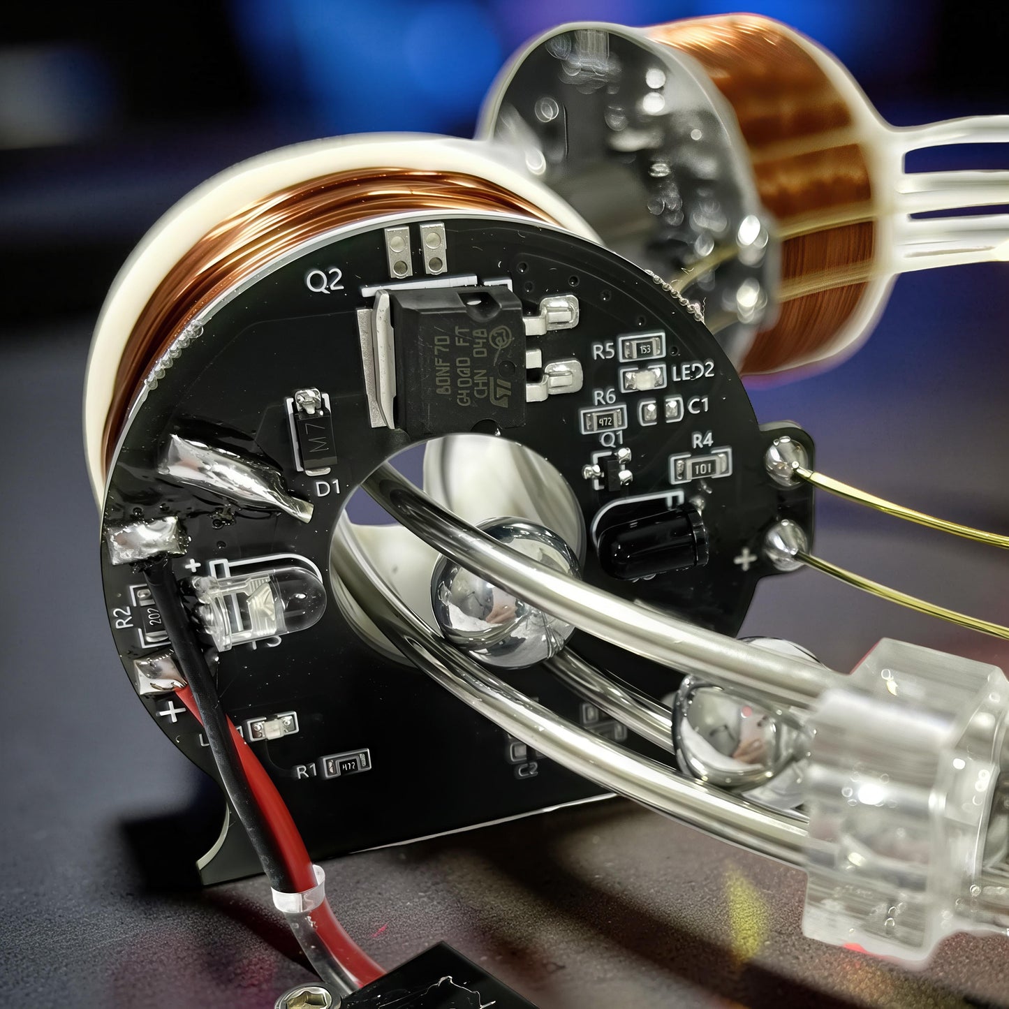 The Curious Mind High-Tech Electromagnetic Coil Accelerator Display features copper coils, a circuit board with components, and metal rods.