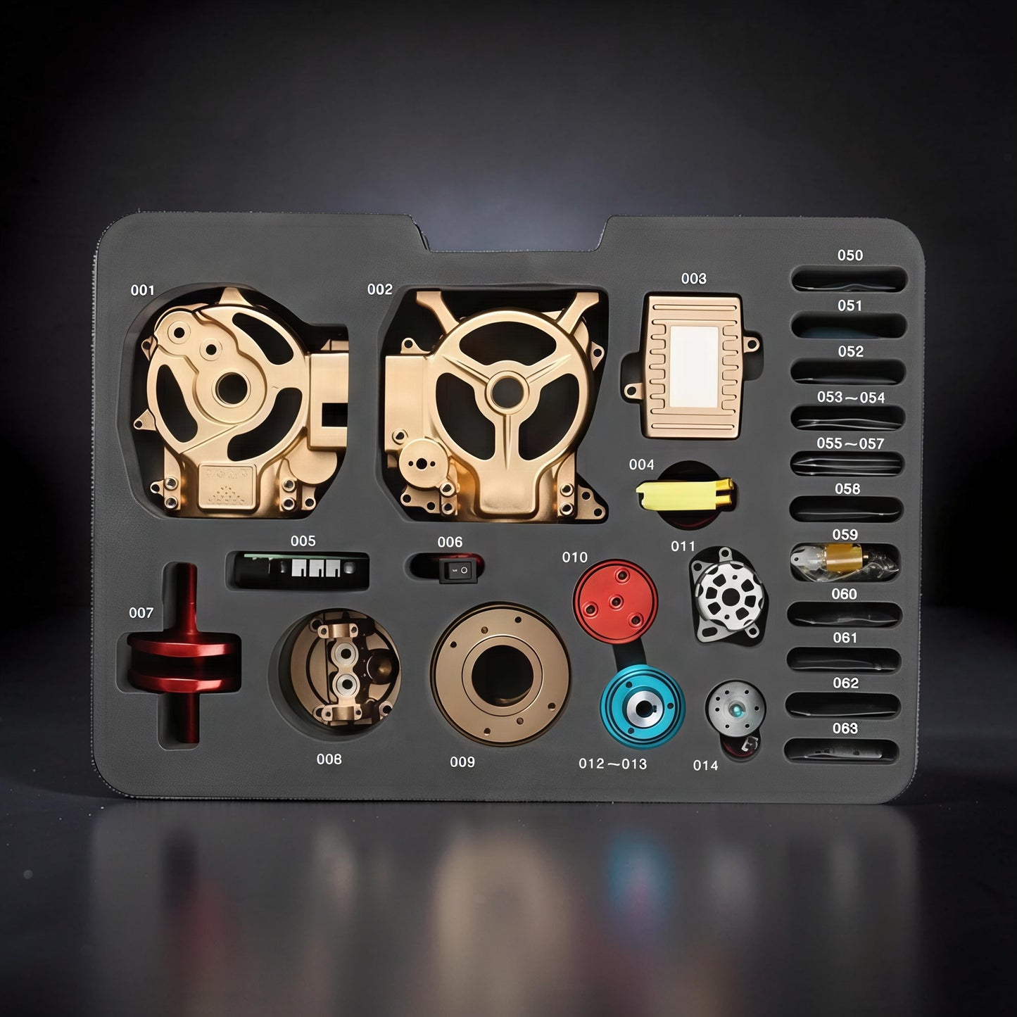 The Curious Mind Mini Single-Cylinder Engine DIY Kit metal parts laid out in a grey organizer tray. Gold and red components are visible.