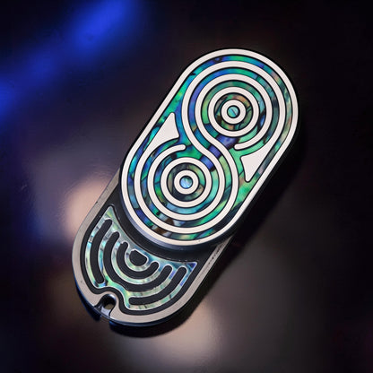 The Curious Mind Fritillary Push Slider fidget toy with iridescent abalone shell inlay and silver accents.