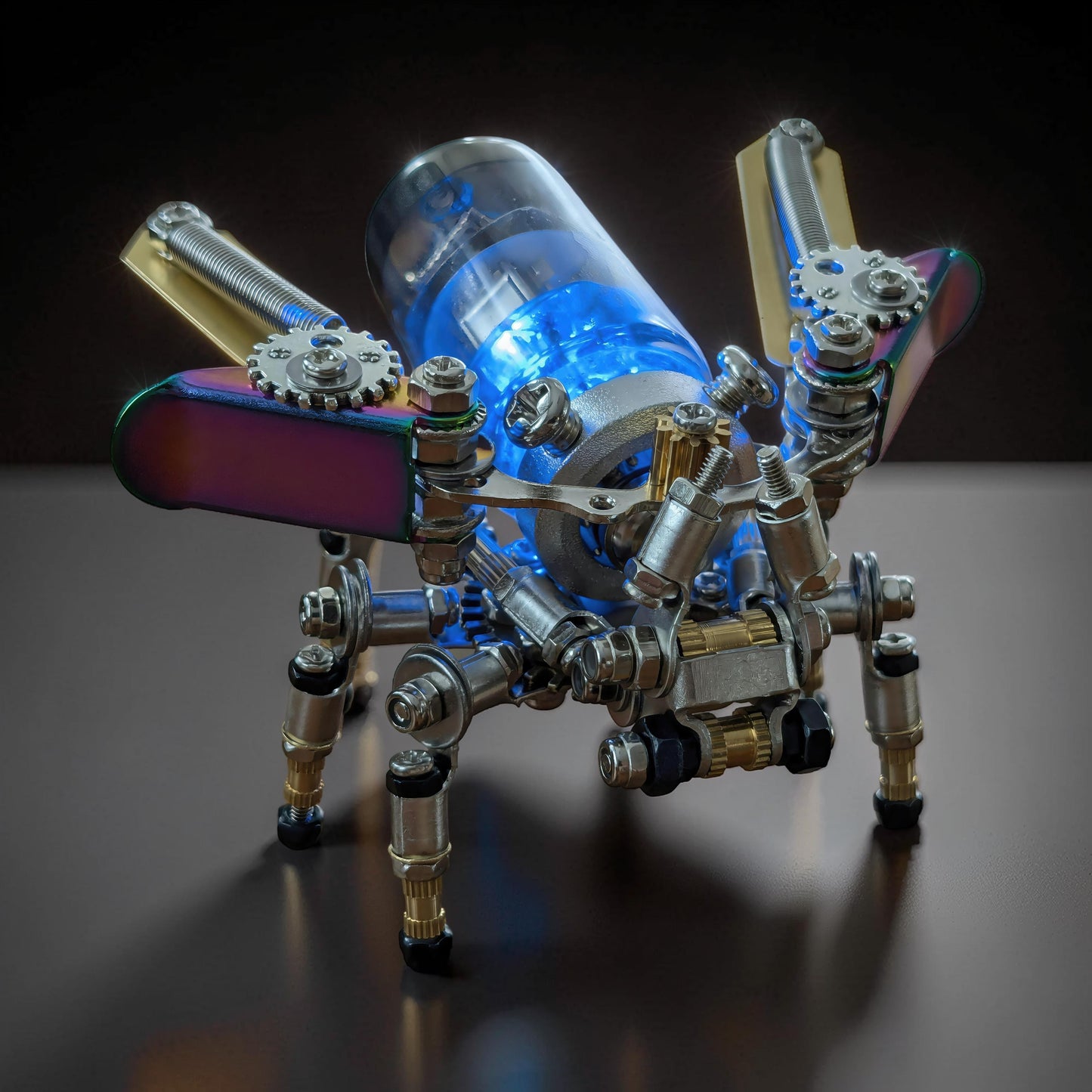 The Curious Mind Firefly punk-style 3D metal model kit with iridescent wings and glowing blue interior.