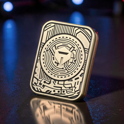 The Curious Mind Three-Body Push Card Fidget is a compact, gold-tone metal fidget toy with intricate circuit board-like engravings and a central shield emblem. It offers tactile feedback for focus and stress relief.