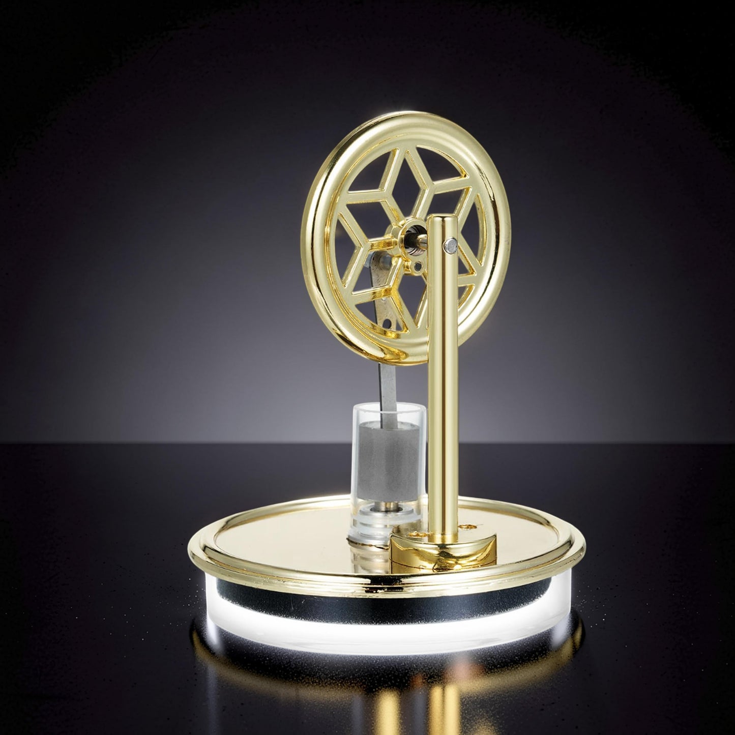 The Curious Mind gold metal Stirling engine display model with decorative wheel and glass cylinder.
