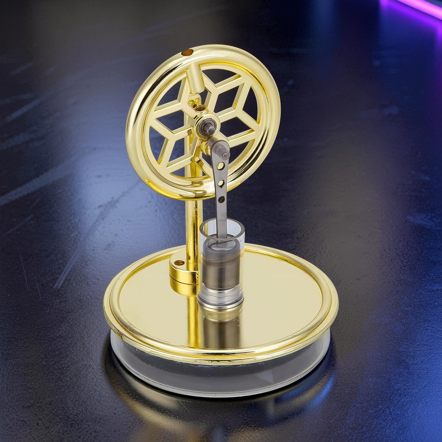 The Curious Mind gold metal Stirling engine display model with a decorative flywheel and visible piston mechanism.