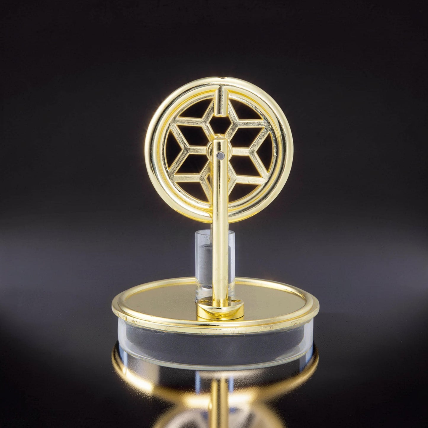 The Curious Mind gold metal Stirling engine display model with a snowflake-like flywheel on a clear acrylic base.