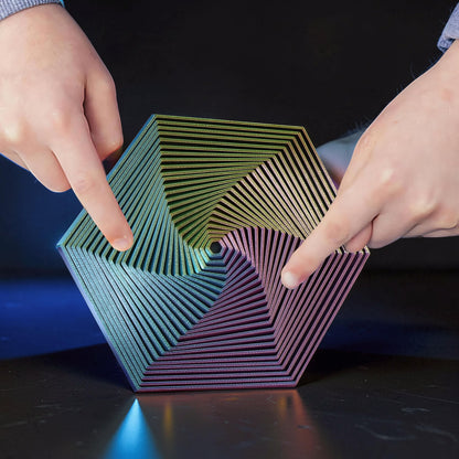 The Curious Mind Hexagon Push Fidget toy with iridescent rainbow colours, made of PLA, being touched by two hands.