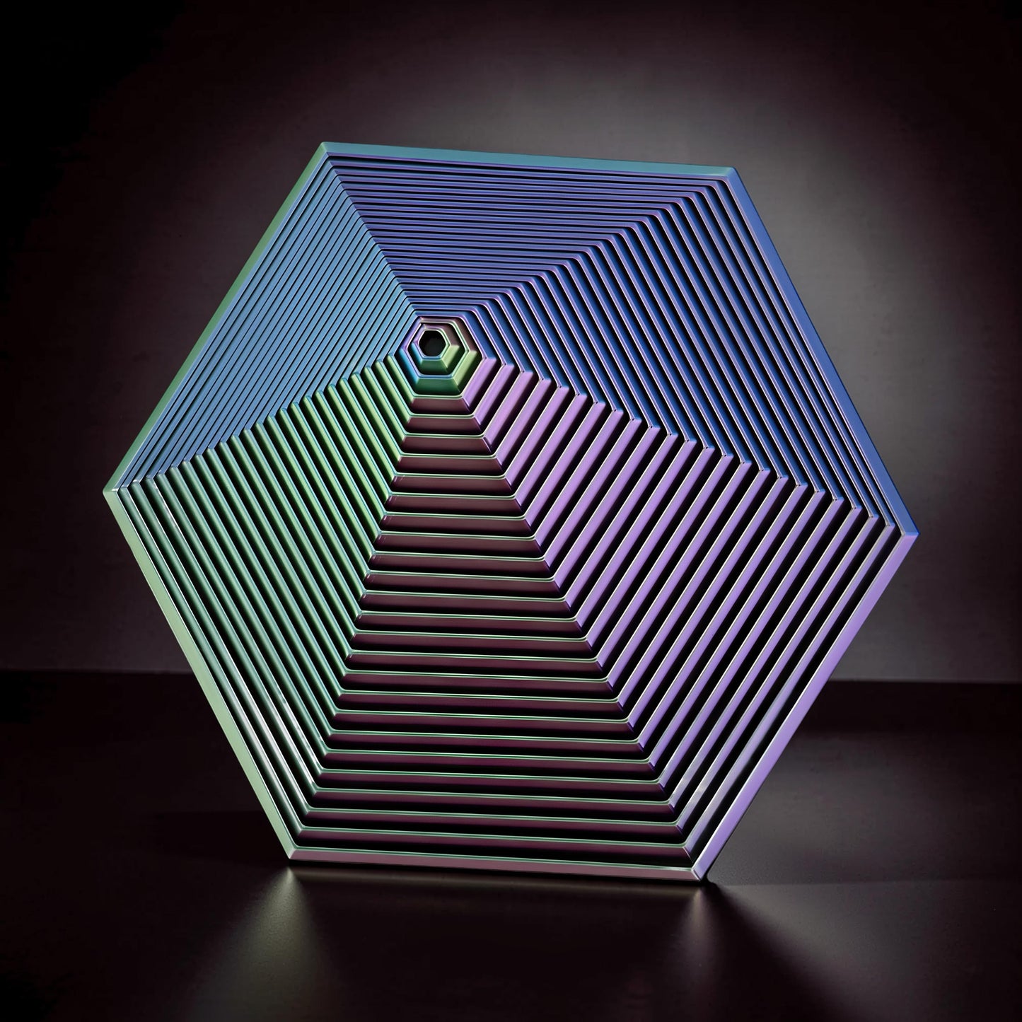 The Curious Mind Hexagon Push Fidget sensory toy with iridescent blue, green, and purple hues, featuring concentric hexagon layers.