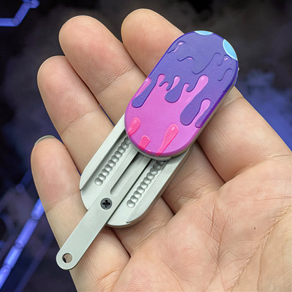 The Curious Mind Ice Cream Push Card Clicker fidget toy in purple and pink, with a metal handle and tactile click mechanism.
