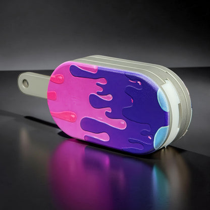 The Curious Mind Ice Cream Push Card Clicker fidget toy with purple and pink dripping design on metal casing.
