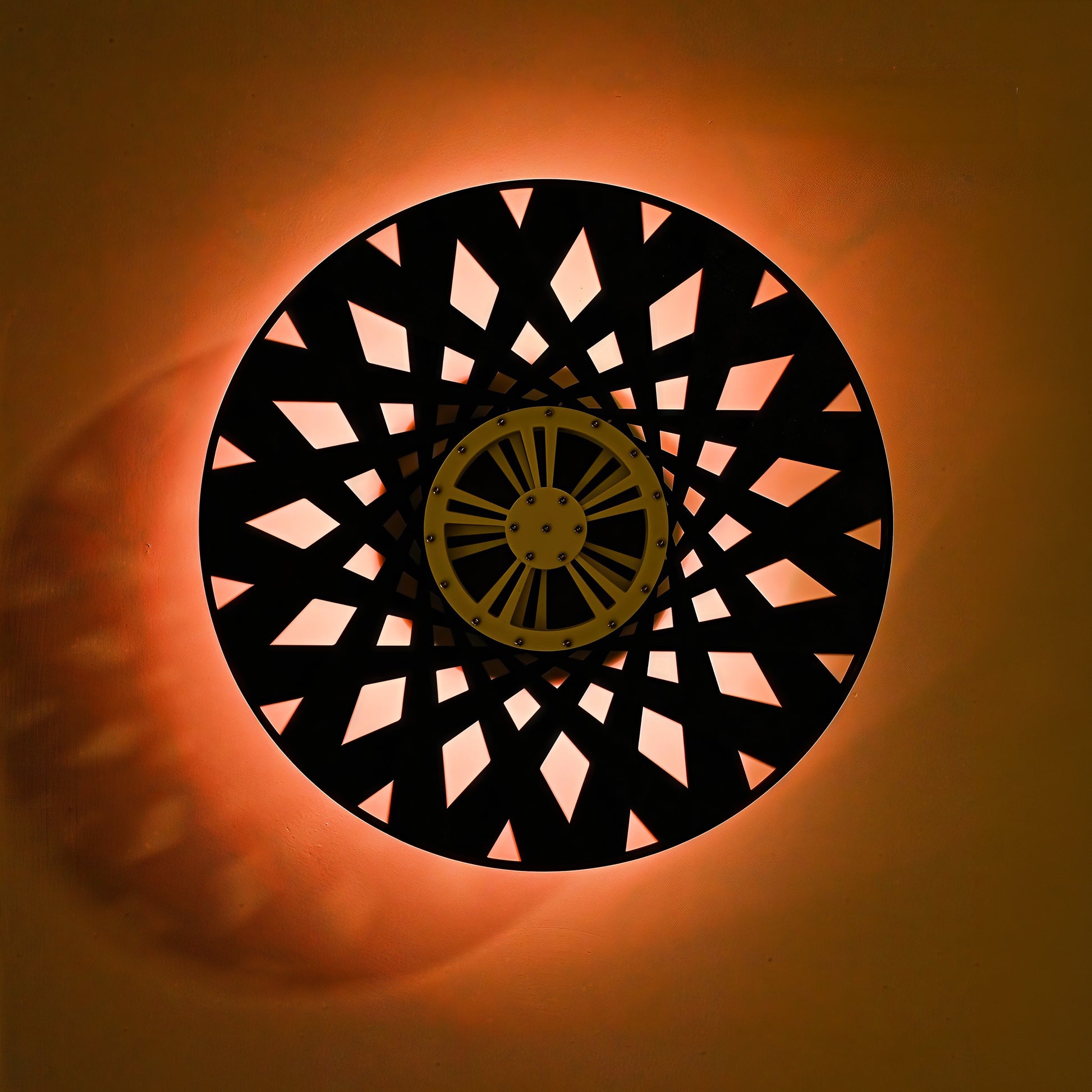 The Curious Mind Time Travel Edition desktop ornament, a black circular kinetic sculpture with a yellow central hub and geometric cutouts, illuminated by warm orange light.