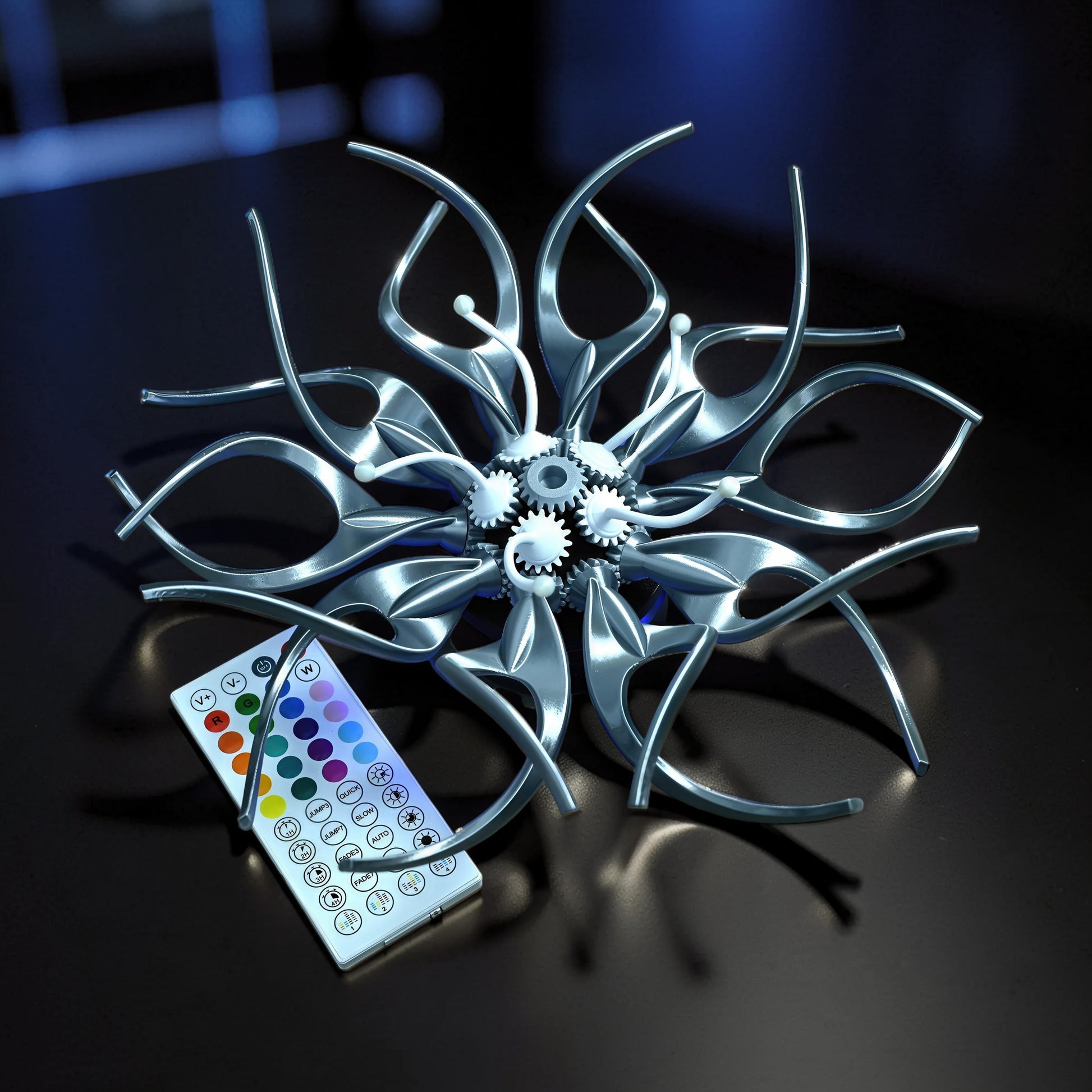 The Curious Mind Mechanical Kinetic Flowers Sculpture Gallery Edition, a silver PLA desk accent with intricate gears and a remote control.