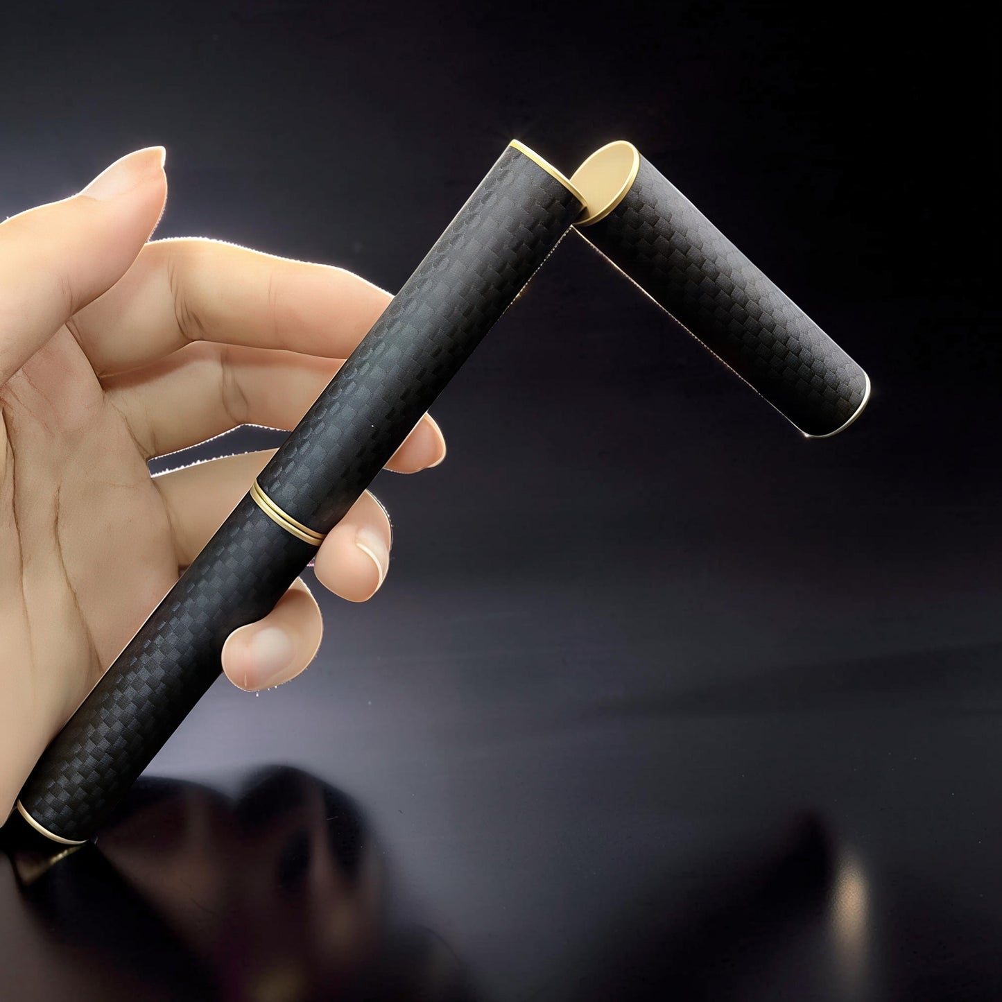 The Curious Mind Magnetic Carbon Fiber Slider with gold accents, held in a hand. Features a sleek black carbon fiber pattern and satisfying magnetic push-and-return action.