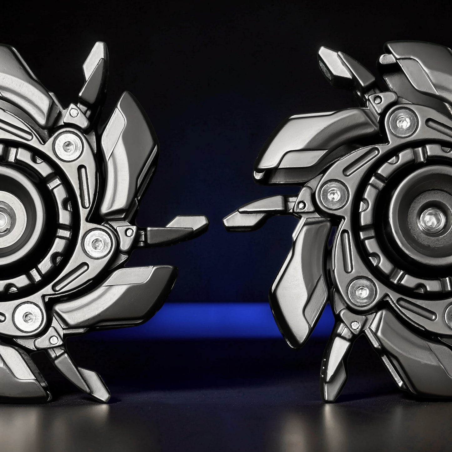 The Curious Mind Open Armour Magnetic Spinner features a metallic gunmetal finish and intricate mechanical detailing. Two spinners are shown close-up against a dark background with a blue illuminated base.