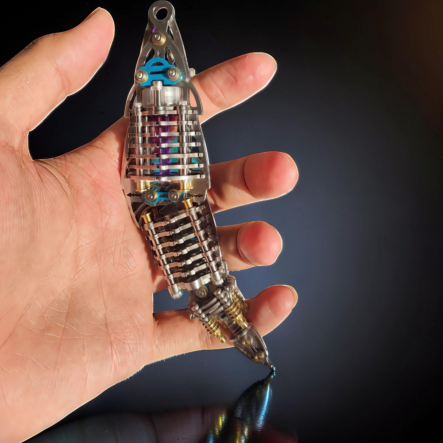 The Curious Mind Mechanical Mantis 3D metal model kit, intricate metal construction with purple accents, held in a hand.