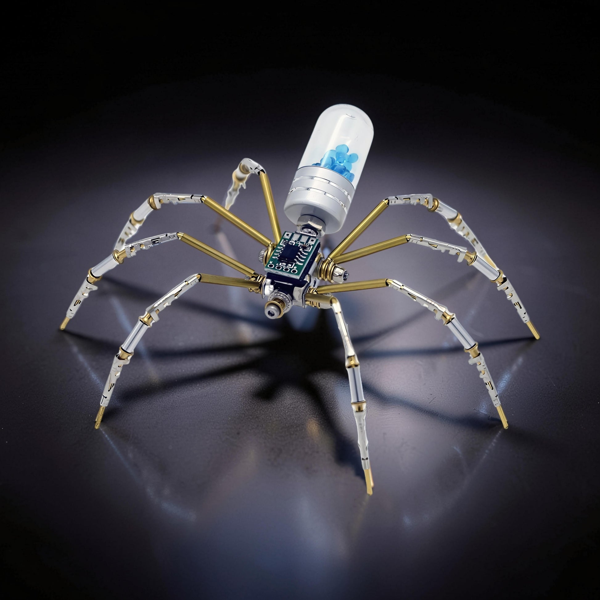 The Curious Mind Style B mechanical spider model kit, made of metal with brass accents and a clear capsule containing blue beads.