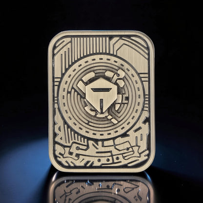 The Curious Mind Three-Body Push Card Fidget, a compact metal clicker with intricate circuit board design and a central shield emblem.