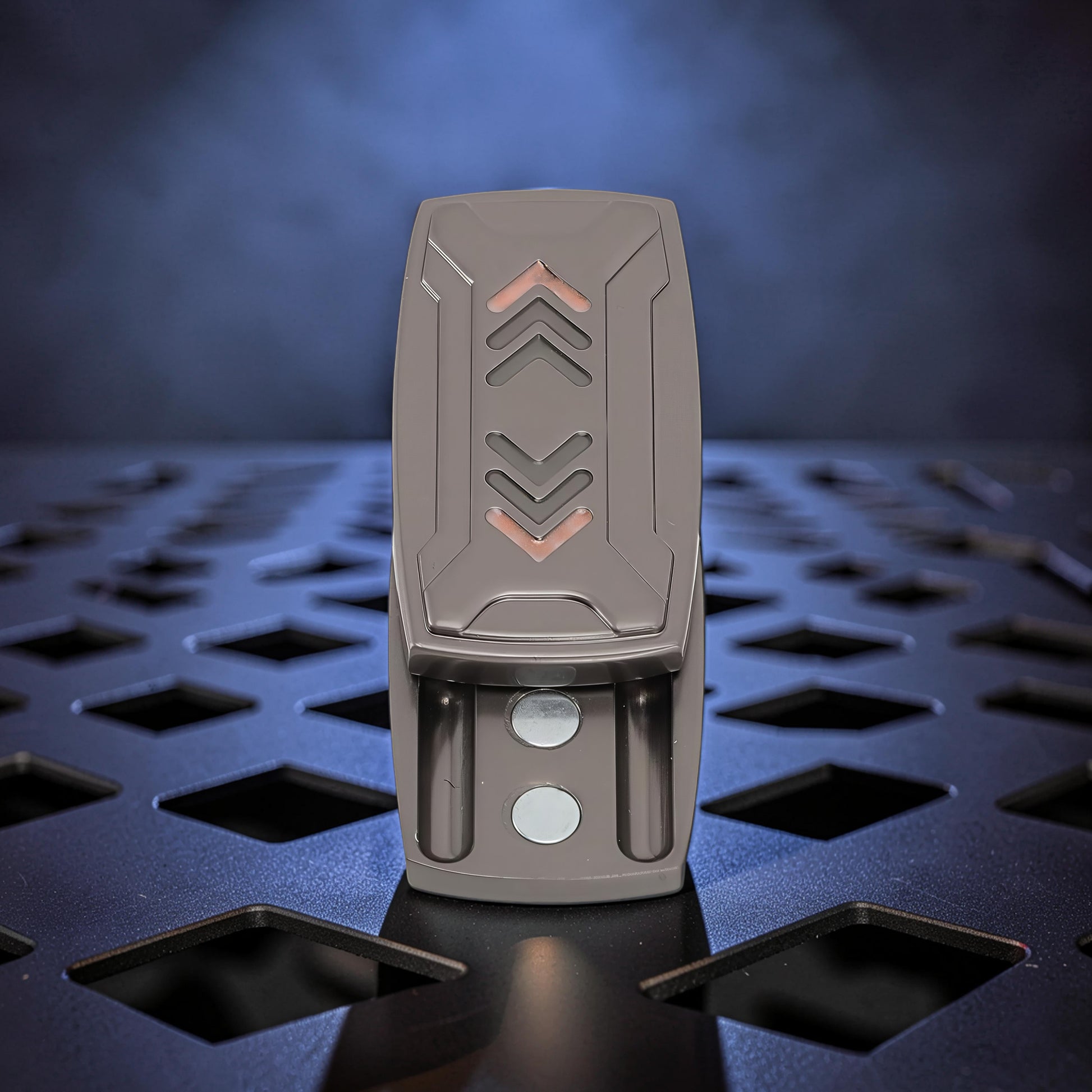 The Curious Mind Arrow Pusher Click Slider fidget toy, a compact metal slider with a dark grey finish and orange arrow accents.