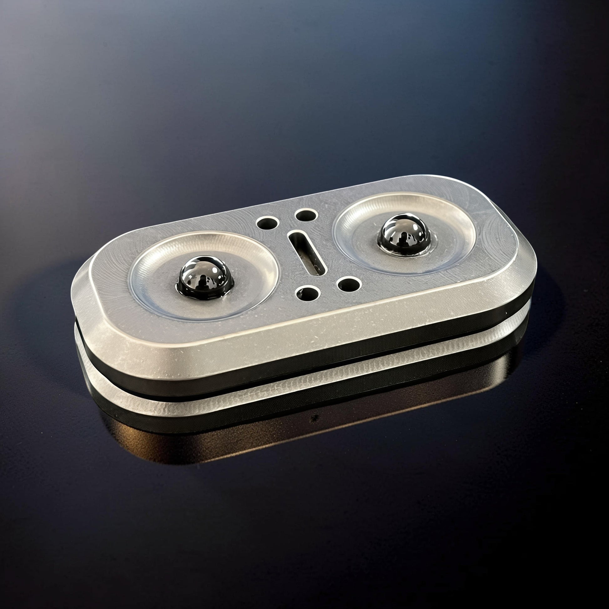 The Curious Mind Owl Push Slider, a compact metal fidget toy with two black magnetic balls and a central slot for sliding action.