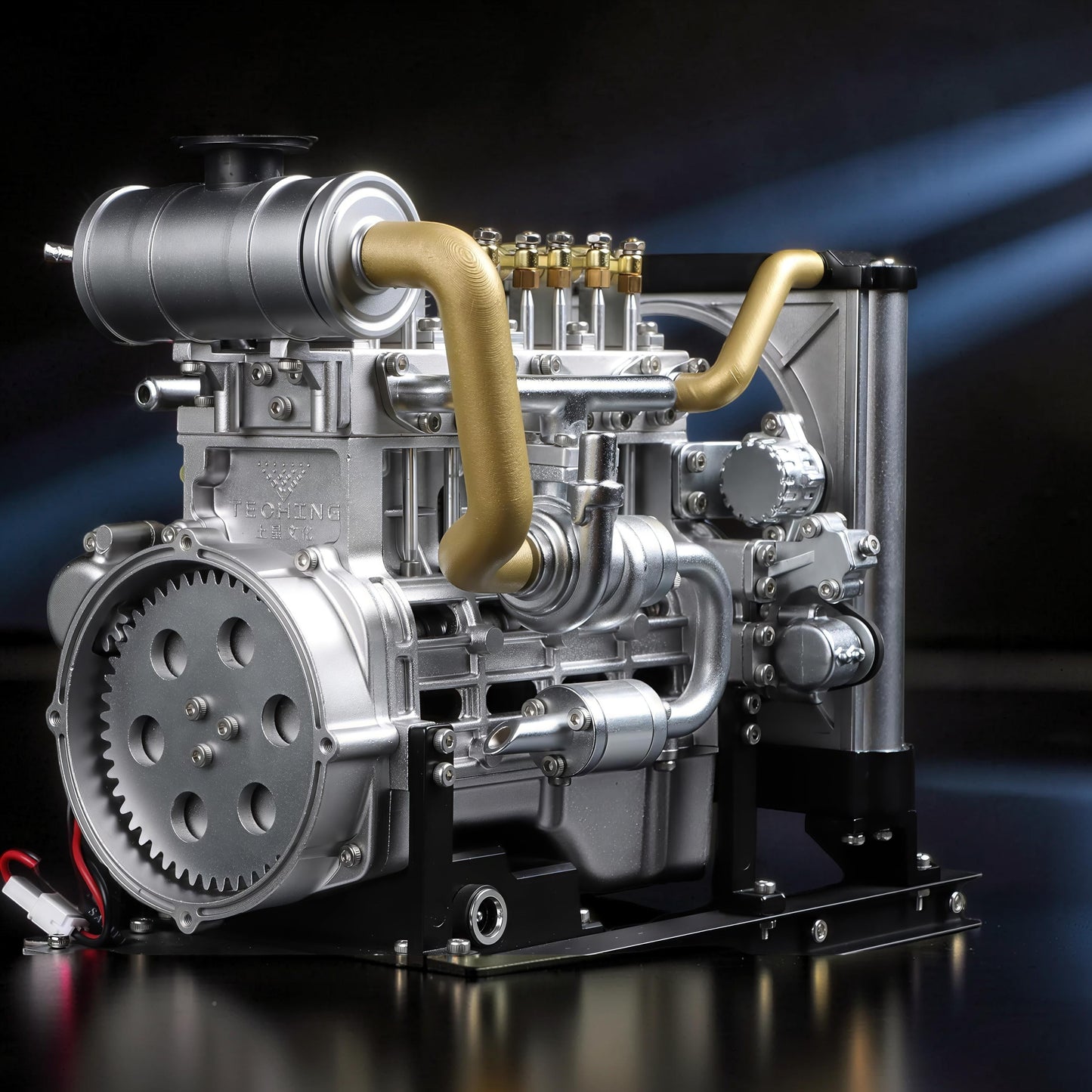 The Curious Mind Mini Diesel 4-Cylinder Engine DIY Kit, a detailed metal mechanical model with gold accents and a black stand.