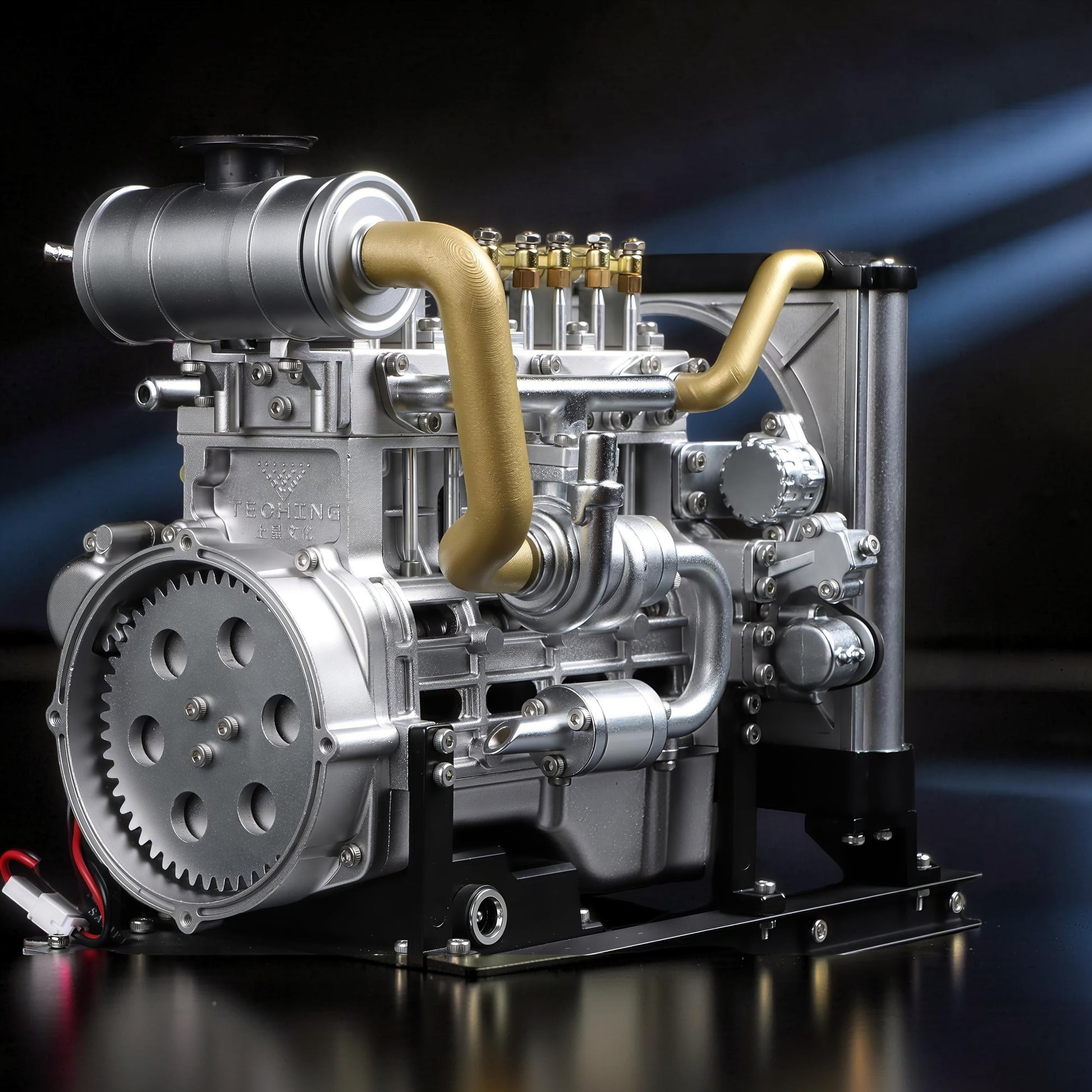 The Curious Mind Mini Diesel 4-Cylinder Engine DIY Kit, a detailed metal mechanical model with gold accents and a black stand.