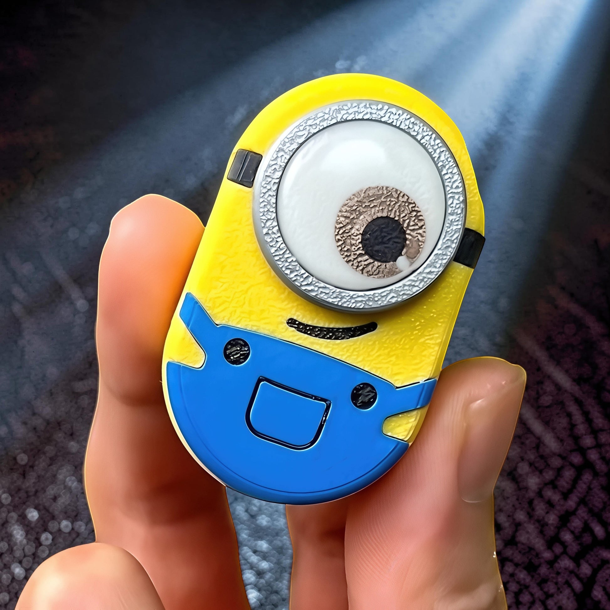The Curious Mind Minion Pocket Push Pop Clicker fidget toy with metal and plastic construction, yellow and blue design.