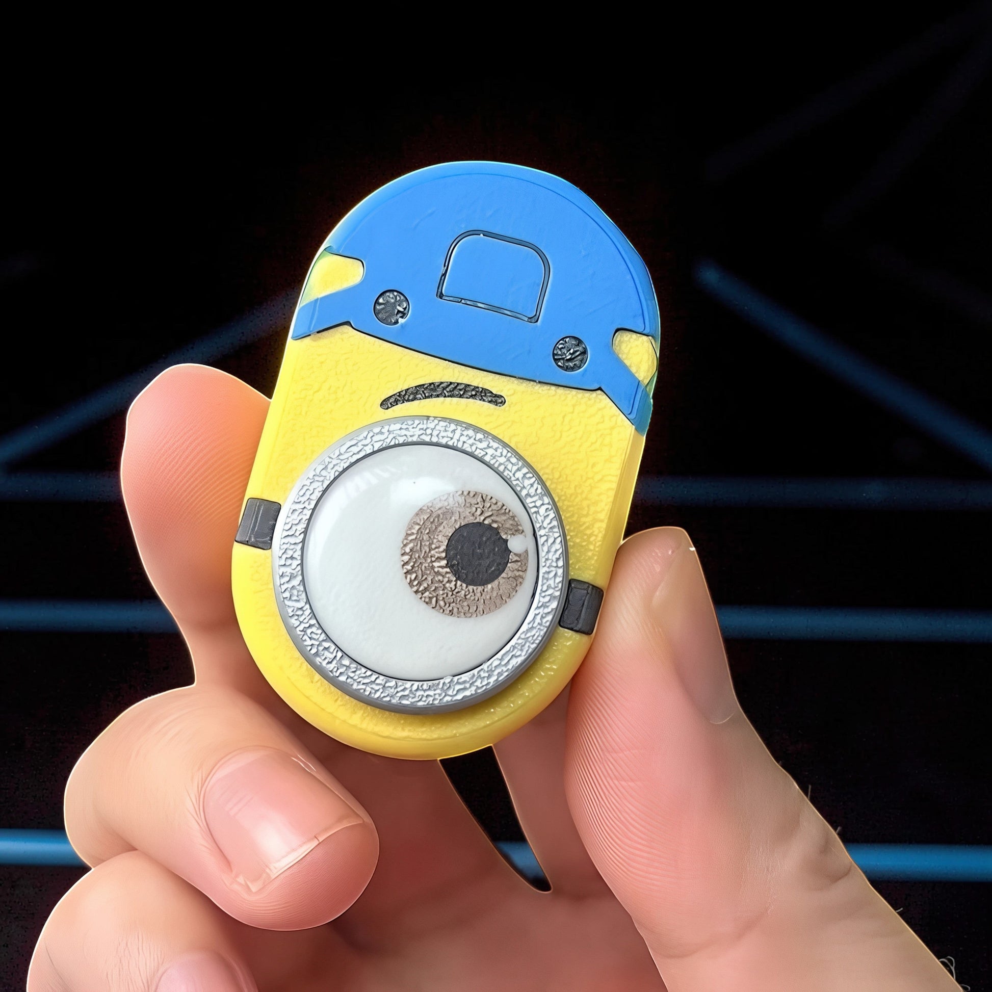 The Curious Mind Minion Pocket Push Pop Clicker fidget toy, yellow and blue metal and plastic, featuring a large eye.