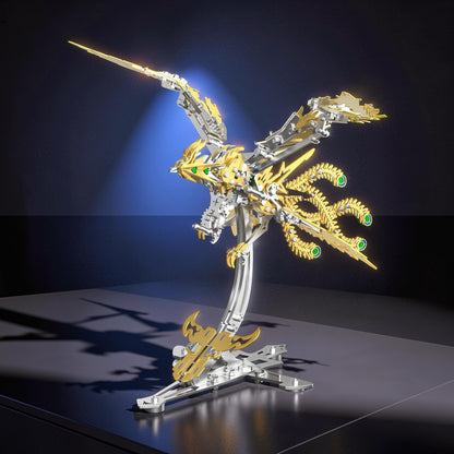 The Curious Mind Phoenix DIY Kit, a silver and gold mechanical bird model with green gem eyes, displayed on a stand.