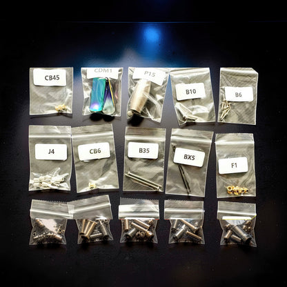 The Curious Mind Punk Wasp 3D metal model kit parts in labeled bags. Includes screws, nuts, and iridescent metal pieces.